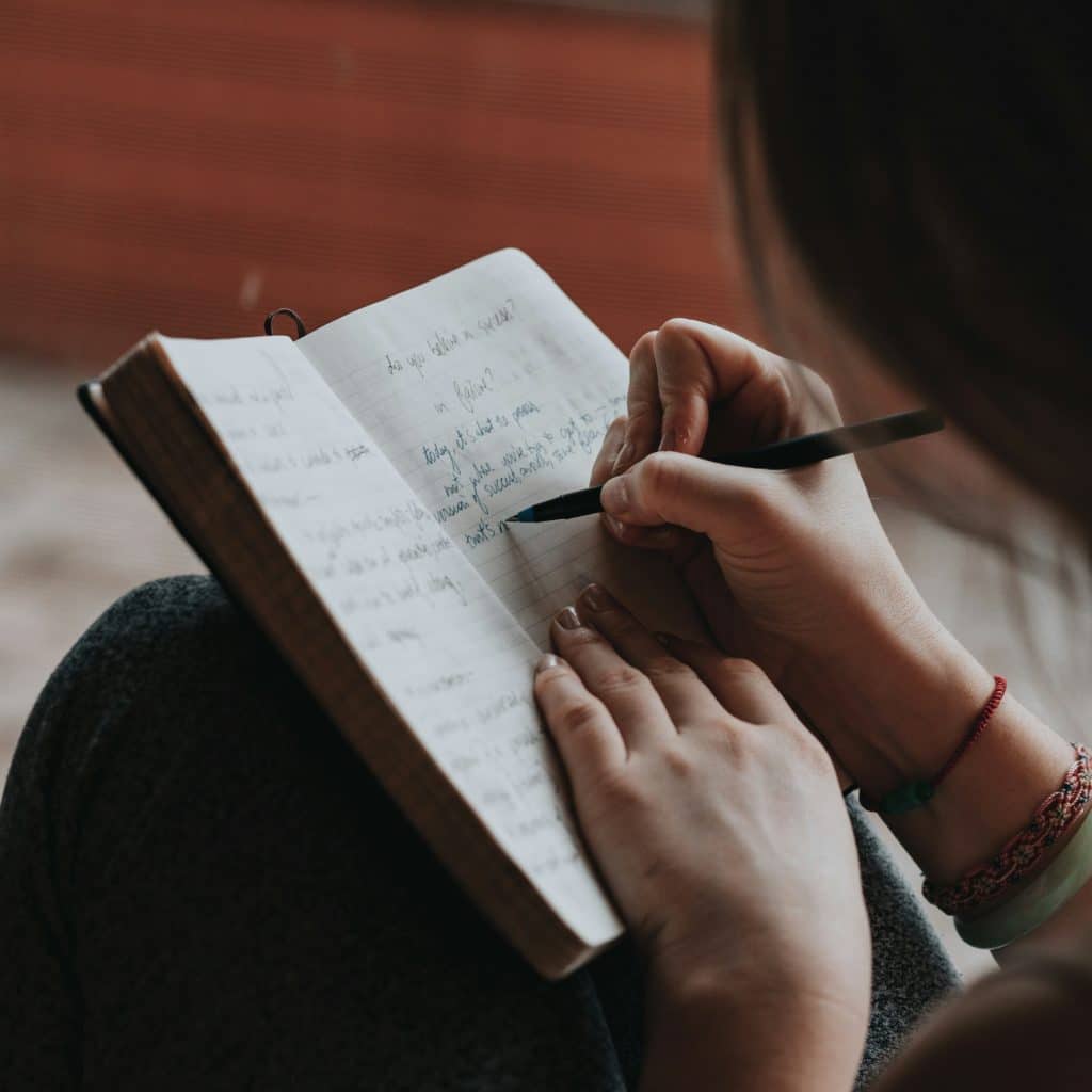 Une femme écrit dans un carnet avec attention