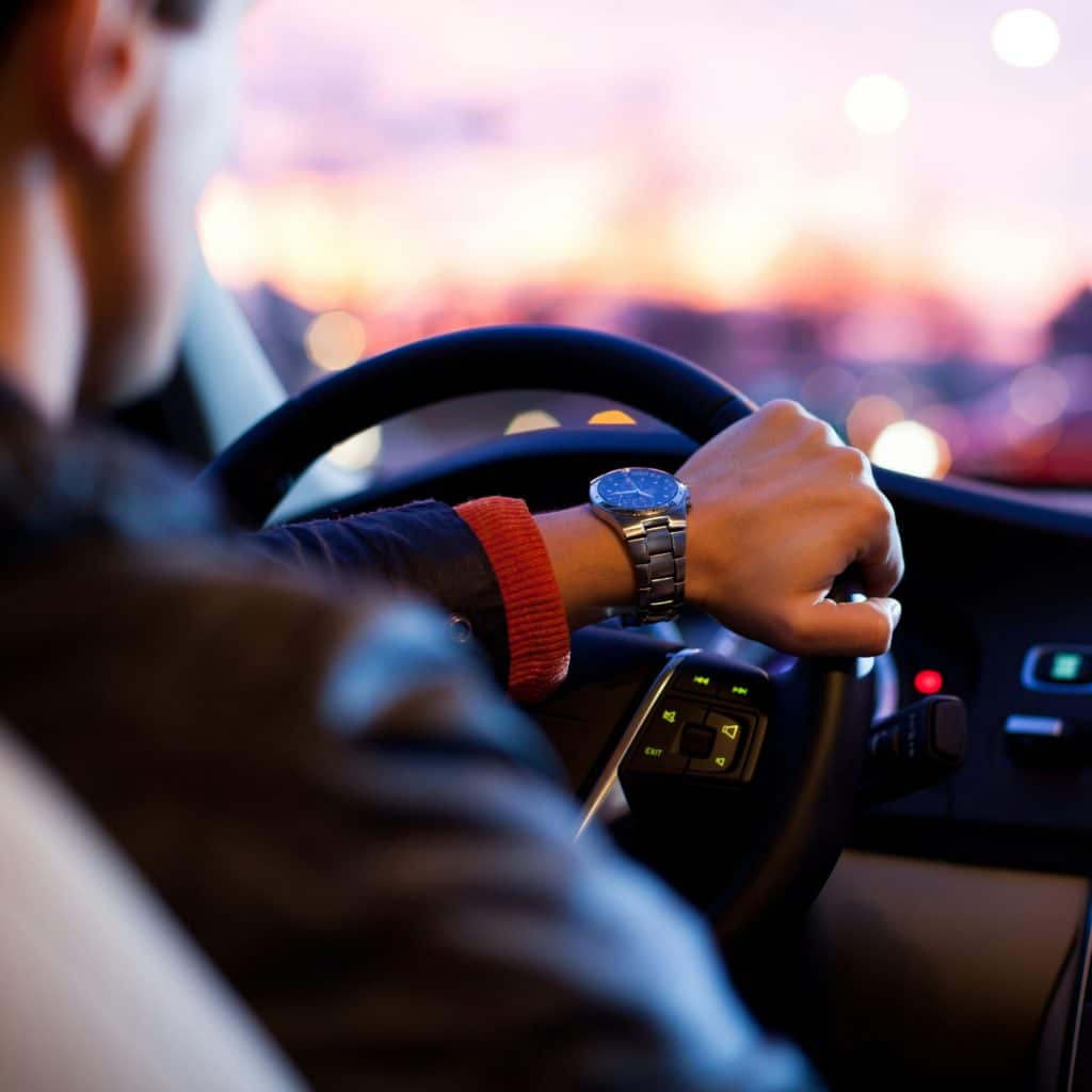 Un homme conduit un voiture au lever du jour