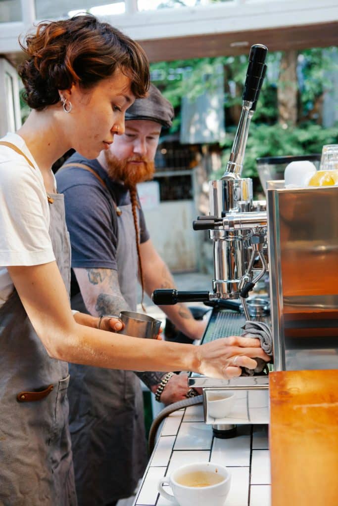 Une barista nettoie une machine à café