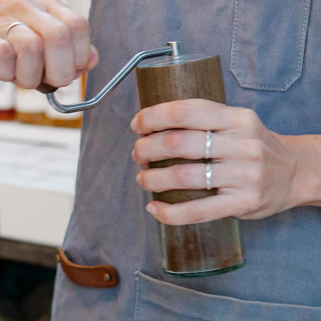 Une femme tient un moulin à café dans une main