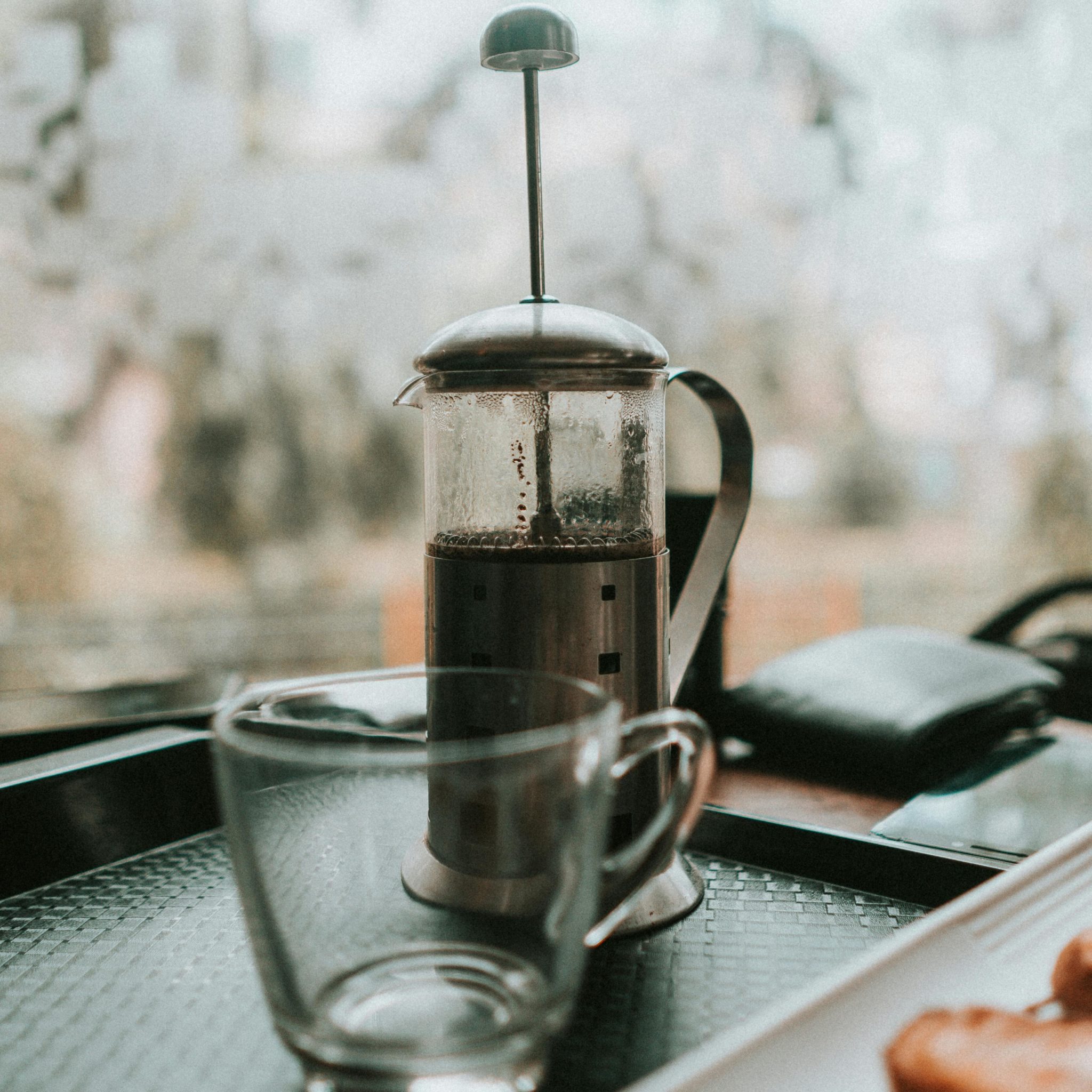 Une french press sur un plateau avec une tasse en verre