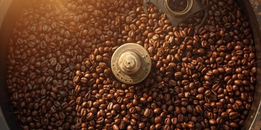 Grains de café fraîchement torréfiés en rotation dans un tambour de torréfaction artisanale.