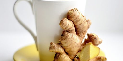 Une tasse de café et du gingembre sont sur une sous tasse