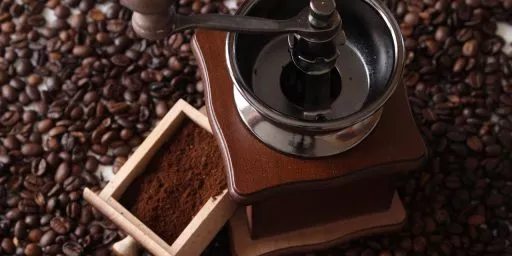 Moulin à café manuel posé sur des grains de café